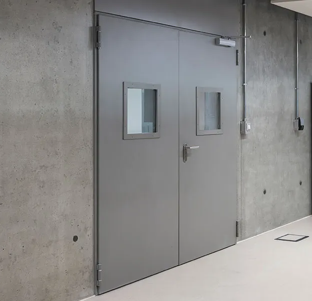 Porta tagliafuoco a due ante grigia TEG con oblò vetrati in contesto tecnico