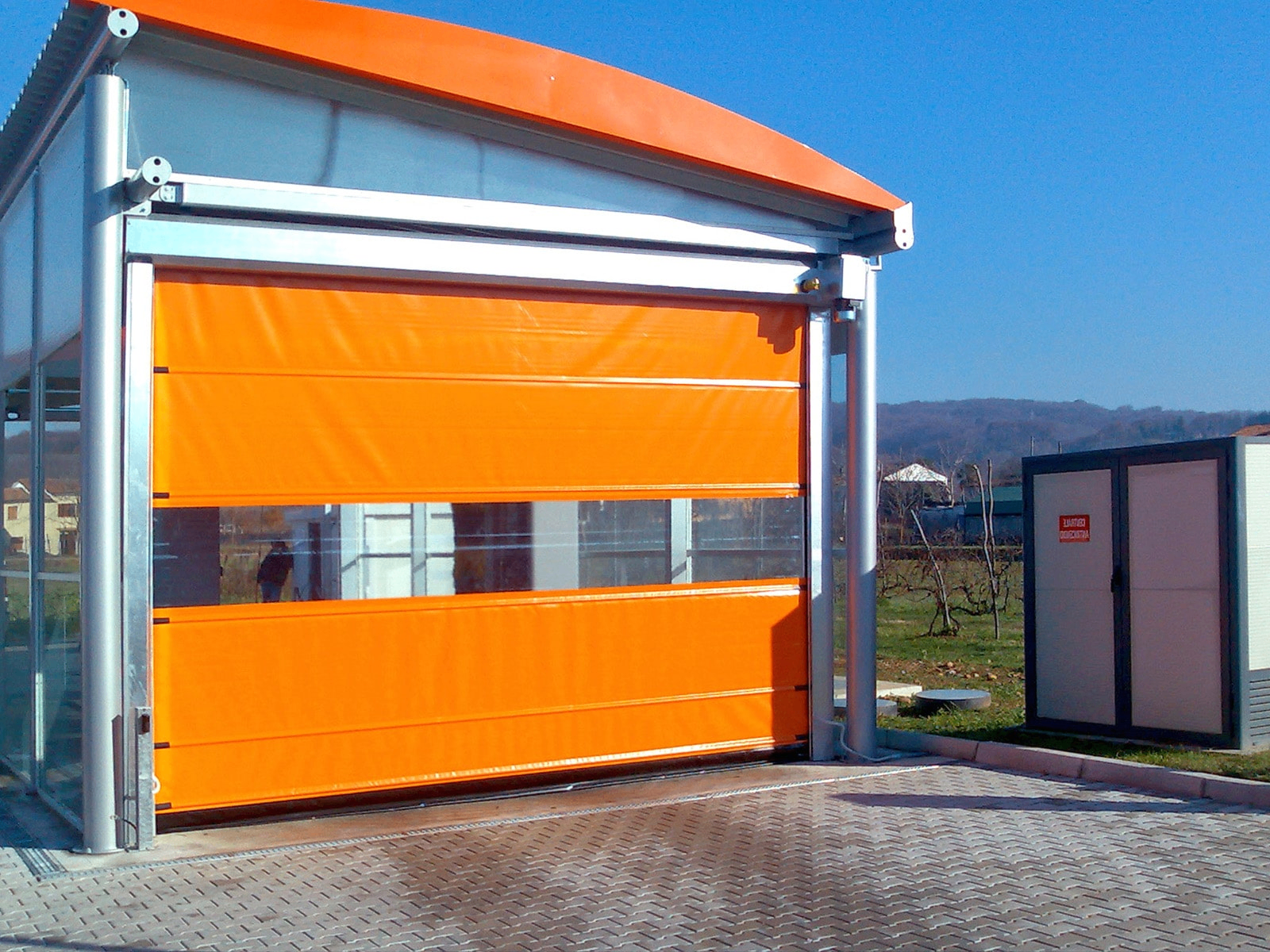 Porta rapida industriale arancione TEG a scorrimento verticale in contesto esterno