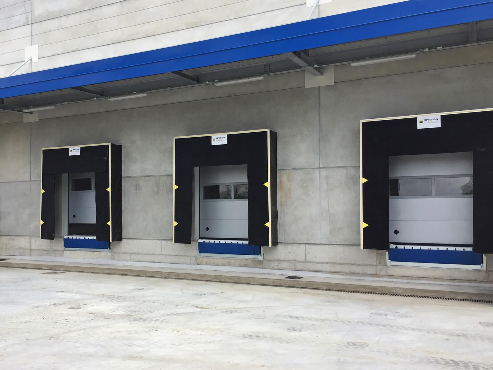 Tre portali isotermici TEG per baie di carico refrigerate con cornici nere e frecce di allineamento
